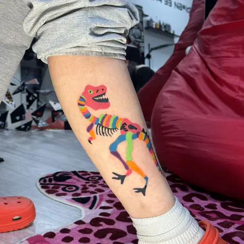 Цветная татуировка динозавра на голени, мультяшный стиль