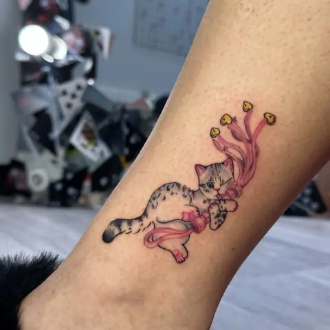 Тату котёнок с розовой лентой на голени, нежный цвет